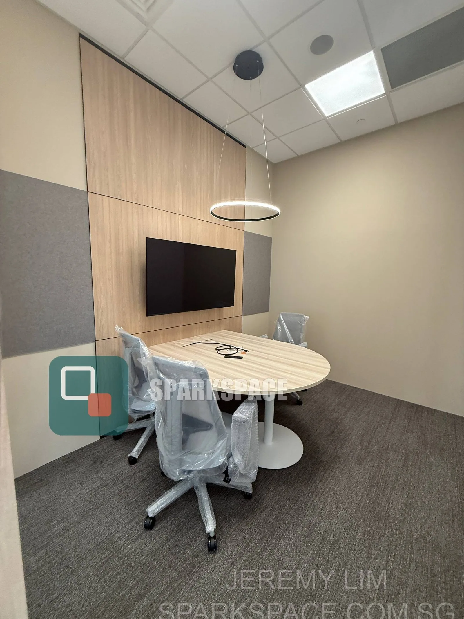 Enclosed fitted meeting room with wall-mounted screen at Keppel South Central
